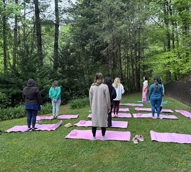 Women practicing on pink mats in the forest